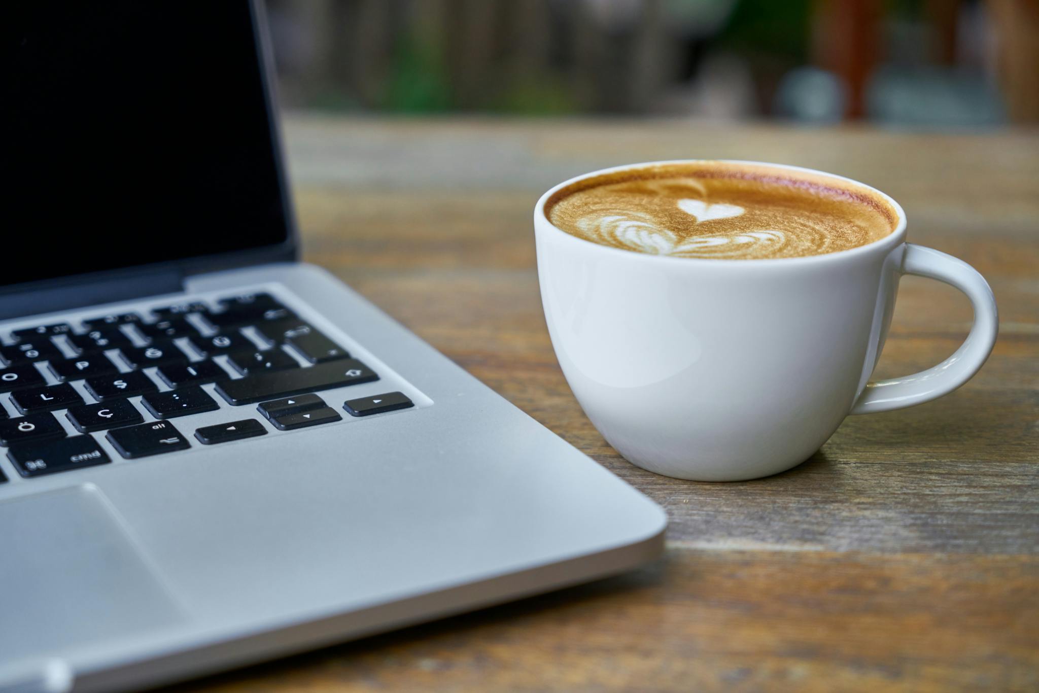 Teacup of Latte Beside Macbook Pro